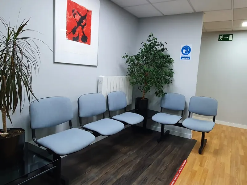 La sala de espera, con sillas azules y plantas