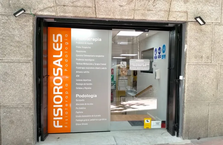 La fachada del centro, con el panel naranja de Fisiorosales y los servicios de fisioterapia y podología escritos en el cristal