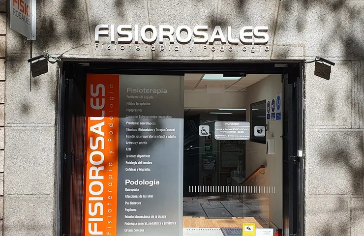 La fachada del centro desde la acera, con el rótulo de Fisiorosales y el panel naranja en la puerta