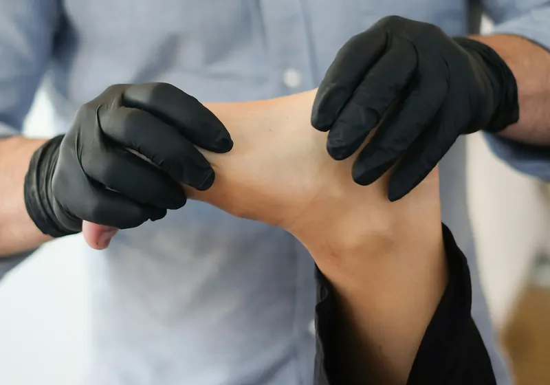 Unas manos con guantes sujetan y exploran el pie de un paciente