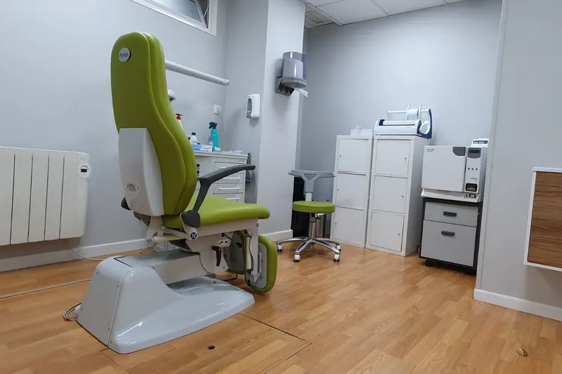 La consulta de podología del centro, con el sillón verde y los armarios del instrumental