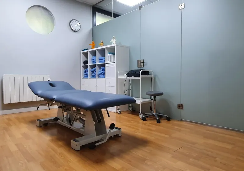 Una sala de tratamiento del centro, con la camilla azul y las toallas en la estantería